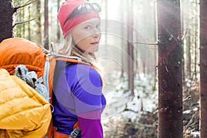 Woman hiking in winter forest sunlight