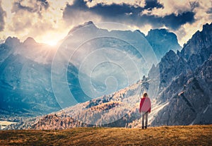 Woman on the hill is looking on the majestic mountains at sunset