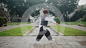 Woman hip hop dancer performing energetic movements in city park. Girl dancing