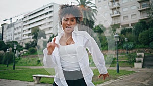 Woman hiphop performer dancing energetic on city street. Girl dancer moving body