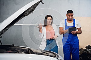 Woman hires a mechanic in overalls to repair a car