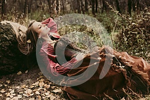 Woman in historical dress resting in autumn forest.