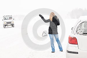 Woman hitchhiking having trouble with car snow