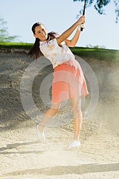 Woman Hitting Golf Ball Out Of A Sand Trap