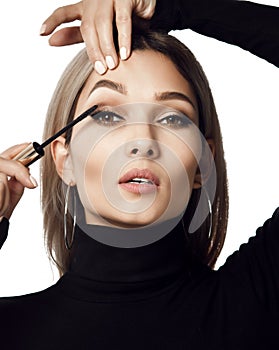 Woman hold black mascara eyelashes doing makeup brush isolated on white