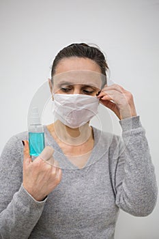 Woman hold blue sanitizer spray and fix face mask photo