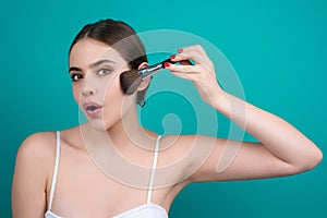 Woman hold blush blusher apply powder visage isolated over studio background. Girl powdering cheeks. Makeup brush