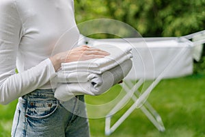 Woman hold clean dry towels near drying rack outdoor