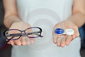 Woman hold contact lenses and glasses in hands. concept of choice of vision protection photo