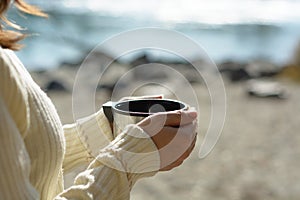 Woman hold cup of tea on beach background. Concept of relax or rest