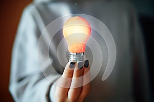 Woman hold in hand glowing light bulb. New idea and innovation concept