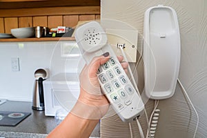 Woman hold landline telephone at the house wall