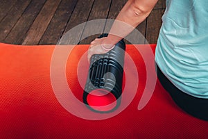Woman hold massage foam roller in morning exercise at red mat