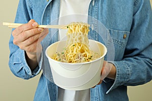 Woman hold paper bowl and chopsticks with cooked noodles