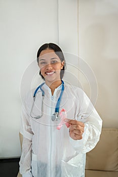 Woman hold pink ribbon for breast cancer awareness. Blurred background. Copy space available