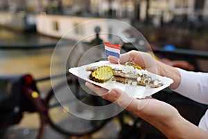 Woman hold plate famous herring fish with onion and cucumber in fastfood market of Amsterdam, Netherlands