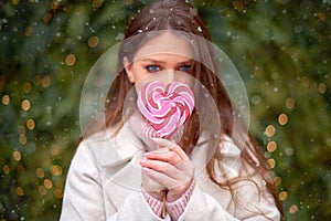 Woman hold red heart-shape lolly-pop on stick in hands. valentine`s day concept