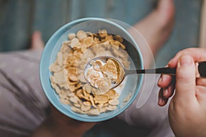 Woman hold sky blue colored bowl of tasty cereal corn flakes