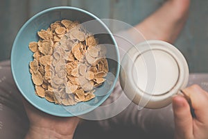 Woman hold sky blue colored bowl of tasty cereal corn flakes