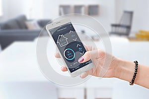 Woman hold smart phone and use smart home control app to monitoring home parameters photo