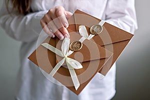 Woman hold two sealed envelopes. invitation envelope with ribbon and wax seal, gift certificate, wedding invitation card