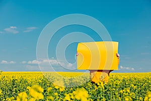 Woman hold yellow paper in rapeseed field