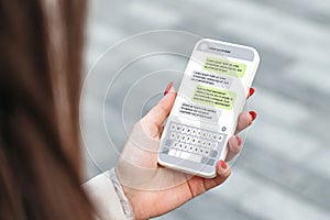 Woman holdind smartphone and texting outdoors. chatting with a phone