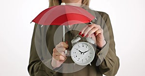 Woman is holding alarm clock and red umbrella