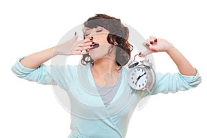 Woman holding alarm clock and yawning