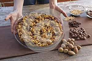 Woman holding an apple pie on wooden table