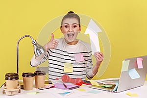 Woman holding arrow pointing up, showing thumb up, satisfied with growth and increase of business.