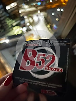 A woman is holding B-52 Shotz in her hand with city lights background