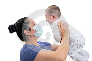 Woman holding baby daughter while wearing disposable medical mask photo
