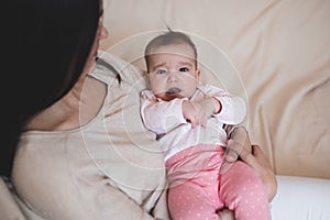 Woman holding baby wear pajamas lying on mother hand crying. Sad child girl have colics and stomach ache at home. Motherhood