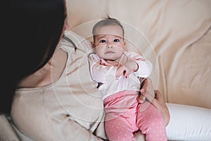 Woman holding baby wear pajamas lying on mother hand crying. Sad child girl have colics and stomach ache at home. Motherhood