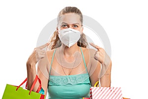 Woman holding bags pointing index fingers at disposable mask