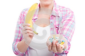 Woman holding banana and tablet pills