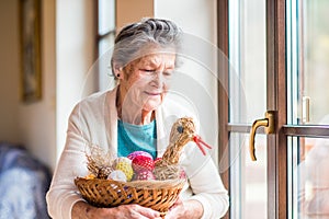 Woman holding basket with Easter eggs and straw hen