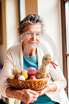 Woman holding basket with Easter eggs and straw hen