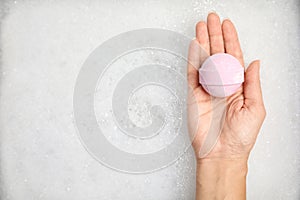 Woman holding bath bomb over foam, top view