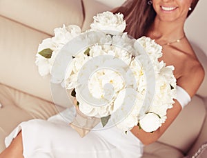 Woman holding beautiful bouquet of white peonies in hands.