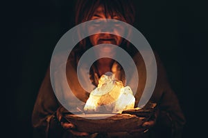 Woman holding a beautiful crystal in her hand, black background.