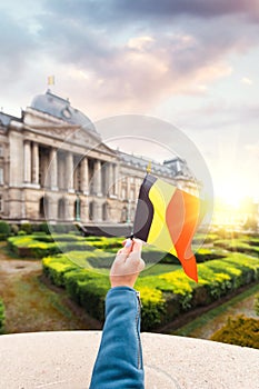 Woman holding Belgium flag in the background of the royal palace in Brussels