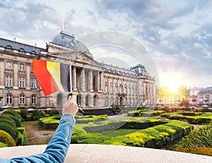 Woman holding Belgium flag in the background of the royal palace in Brussels