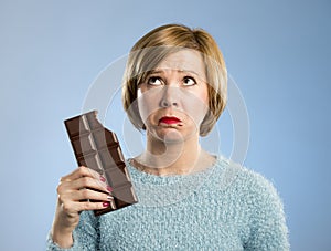 Woman holding big chocolate bar with mouth stains and guilty face expression in sugar addiction
