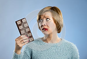 Woman holding big chocolate bar with mouth stains and guilty face expression in sugar addiction