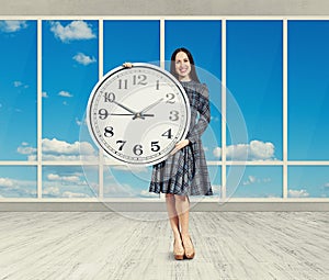 Woman holding big clock, smiling