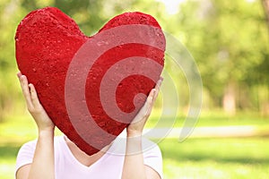 Woman holding big red heart before her face