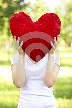 Woman holding big red heart before her face