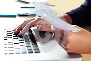 Woman holding bills and paying bills on computer